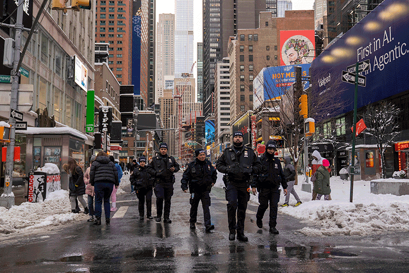 Four NYPD officers walk abreast on Broadway near 49th Street in Times Square.